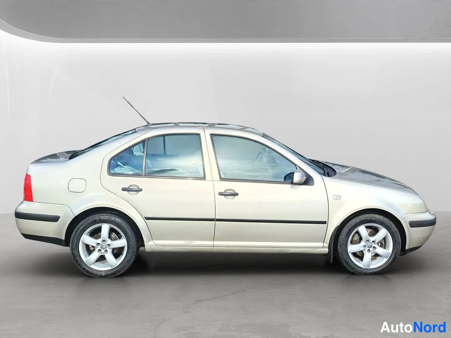 Sivulta: Beige neliovinen henkilöauto kuvattuna suoraan sivulta, harmaassa studiossa.