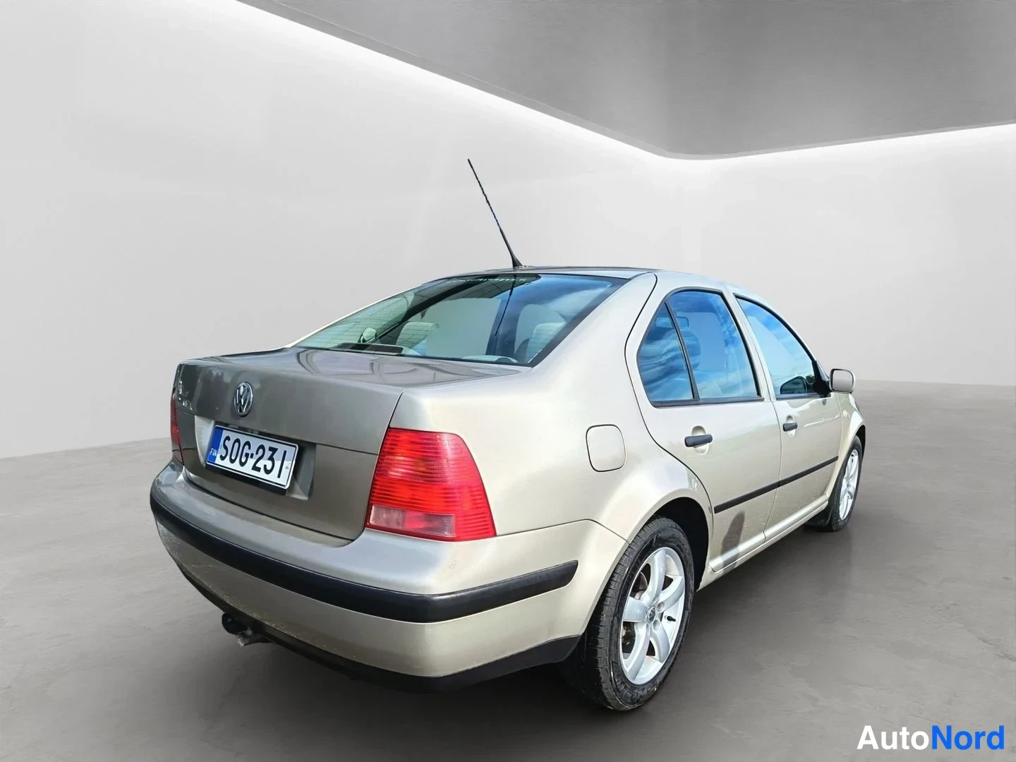 Takaviisto: The rear and right flank of a beige Volkswagen sedan in an indoor studio.