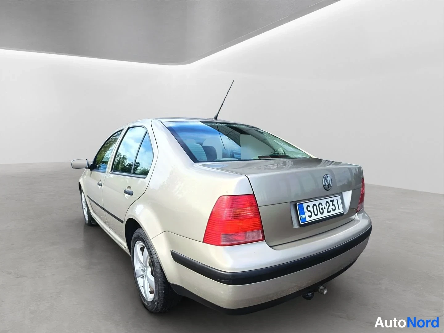 Takaviisto: The rear and left flank of a beige VW sedan parked indoors.