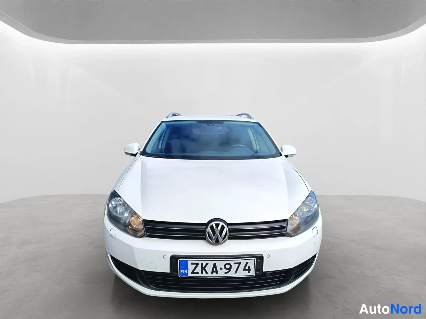 Edestä: Valkoinen Volkswagen station wagon suoraan edestä kuvattuna. Kuvatun autoon kuuluva rekisterikilpi on lukiessa siisti.