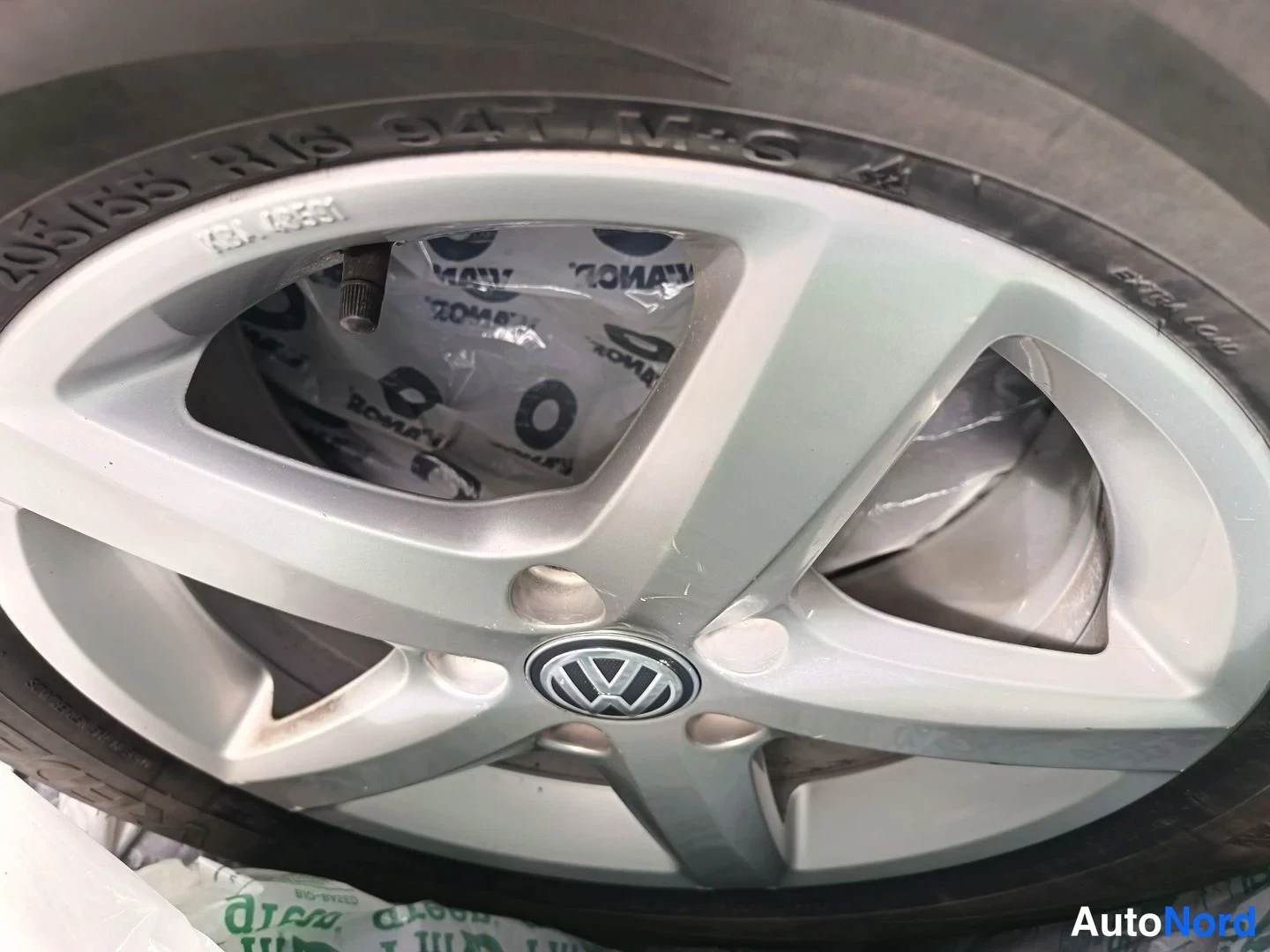 Yksityiskohta: Lähikuva Volkswagenin hopeisesta viisipuikaisesta kevytmetallivanteesta, renkaiden sivuseinässä lukee 205/55 R16 94T M+S.