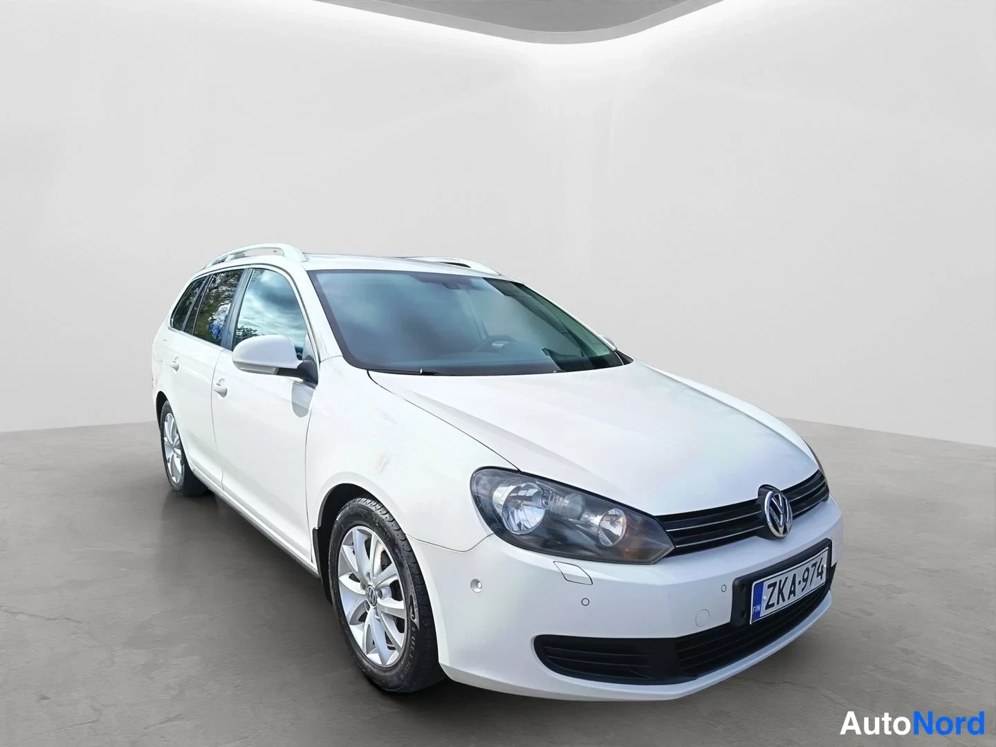 Etuviisto, nokka oikealle: Valkoinen Volkswagen station wagon etuviistokuvassa. Leveät alumiini-renkaat ja katon raidat ovat selvästi erottuvia.