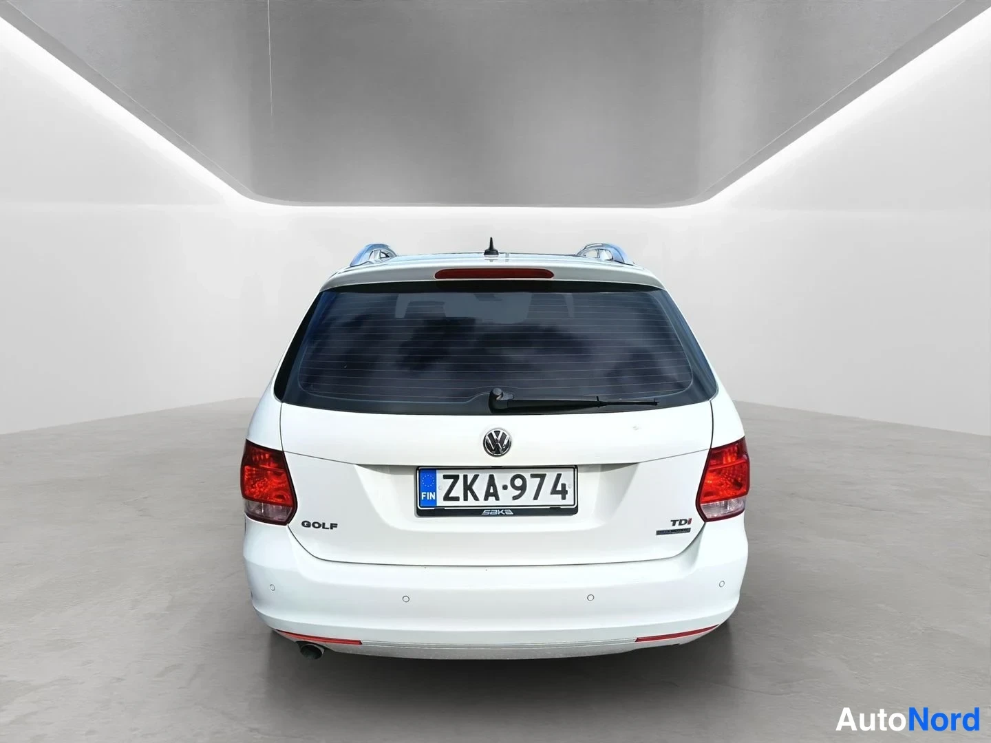 Takaa: Direct rear view of the white car. The VW logo is in the center above the license plate which reads. The red tail lights flank the plate, and the 'GOLF' and 'TD