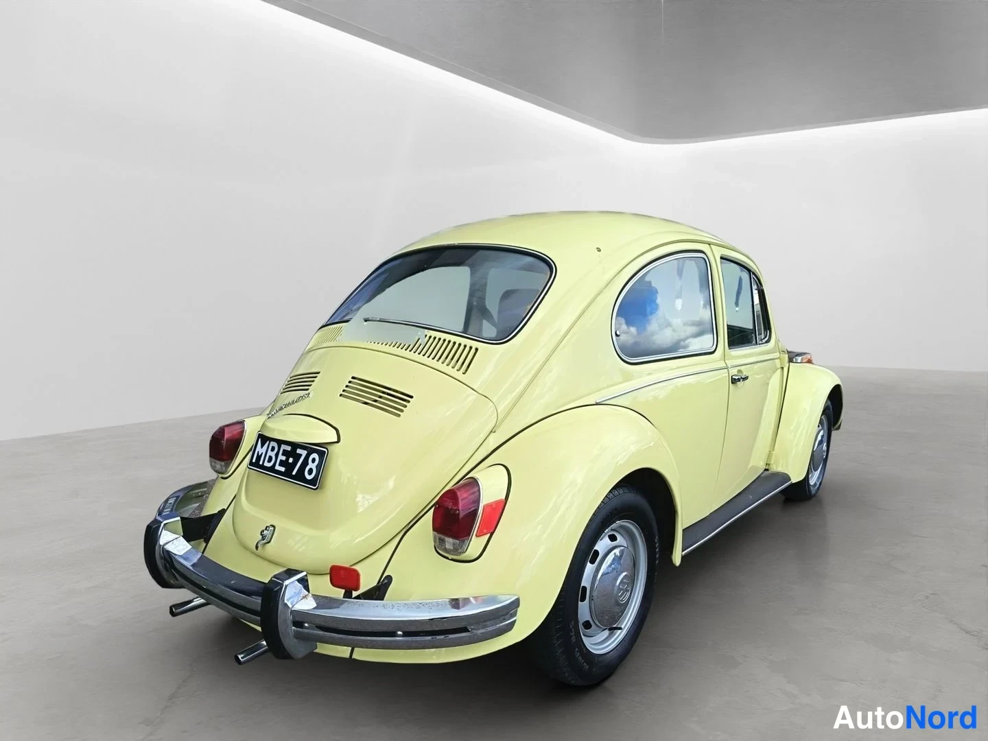 Takaviisto: Keltainen Volkswagen Kupla takaa oikealta kuvattuna, rekisterikilpi, kromipuskurit ja selkäkansi ilmastointiluukuineen näkyvät.