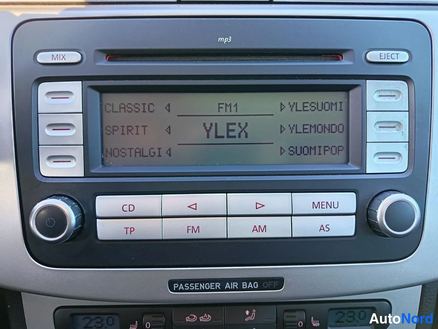 Muu: Radio-CD-yksikön lähikuva: näytöllä FM1-kanavalista (YLEX, Ylesuomi, YleMondo, Suomipop), MP3-merkintä ja PASSENGER AIR BAG OFF -tarra.