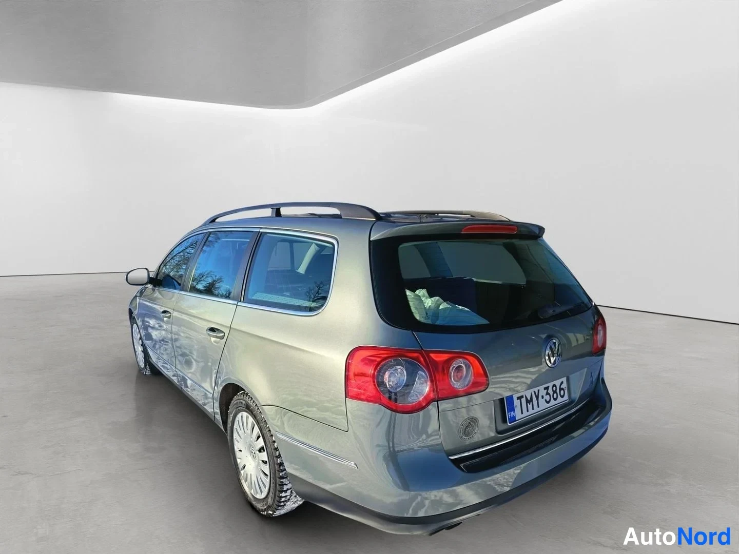 Takaviisto: Takakulmasta kuvattu harmaanmetallinen farmariauto studiossa: takavalot, VW-merkki ja rekisterikilpi näkyvät, samoin auton vasen sivu ja kattokaiteet.