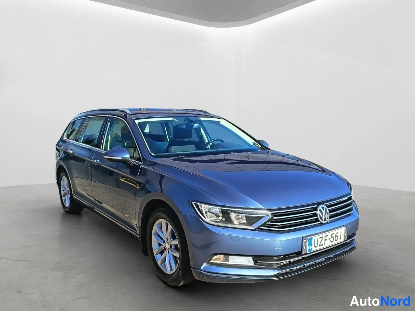 Etuviisto, nokka oikealle: Sininen Volkswagen Passat Variant farmari etuviistosta vasemmalta; kylki ja etupää näkyvät selkeästi, rekisteritunnus.