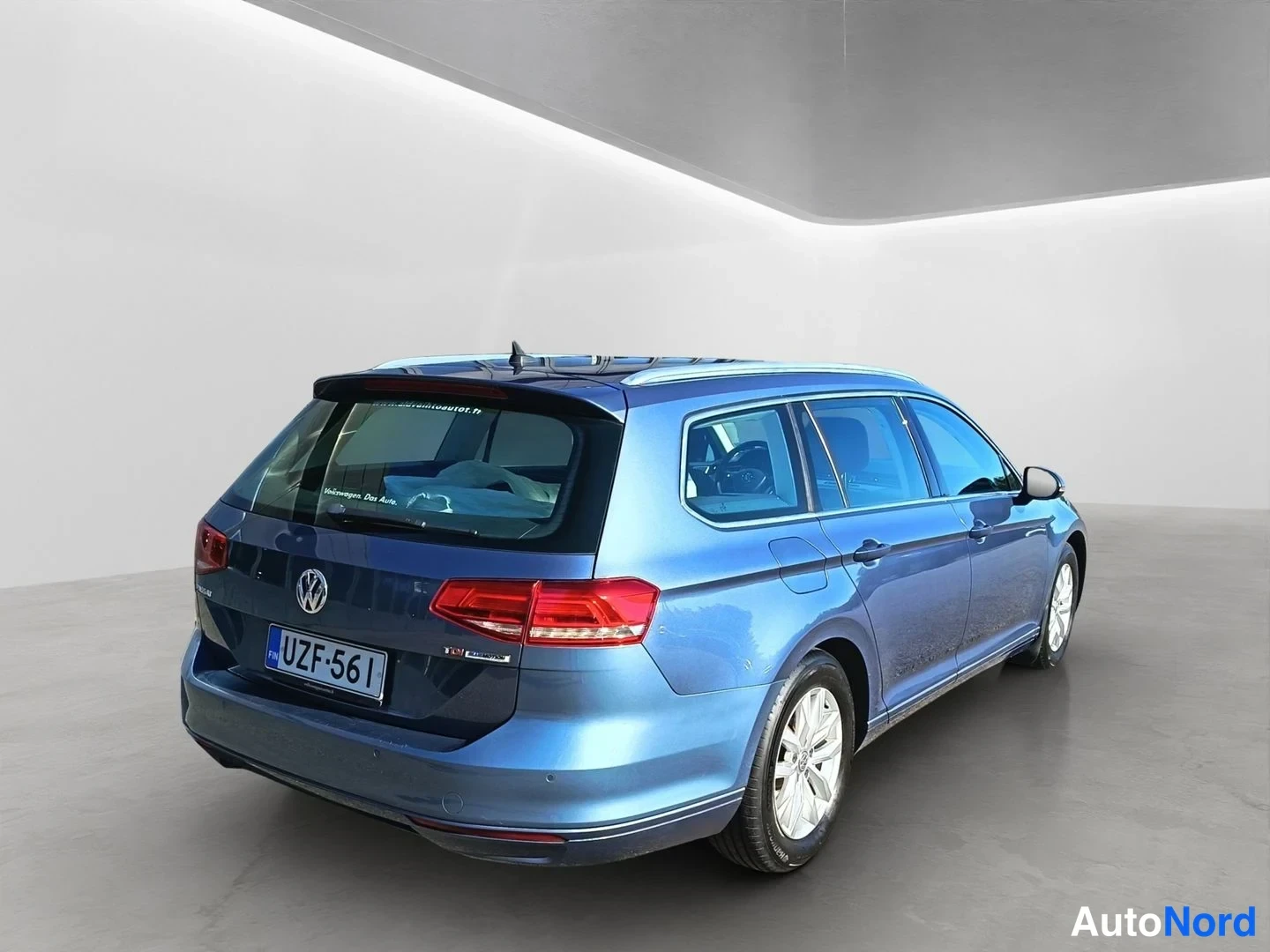Takaviisto: Blue Volkswagen Passat Variant station wagon photographed from a rear three-quarter angle showing the tailgate, right flank and wheel against a white studio wal