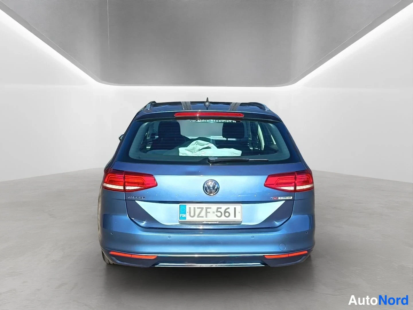 Takaa: Rear view of blue Volkswagen Passat Variant with tail lights, VW badge, license plate, roof rails and rear parking sensors on the bumper