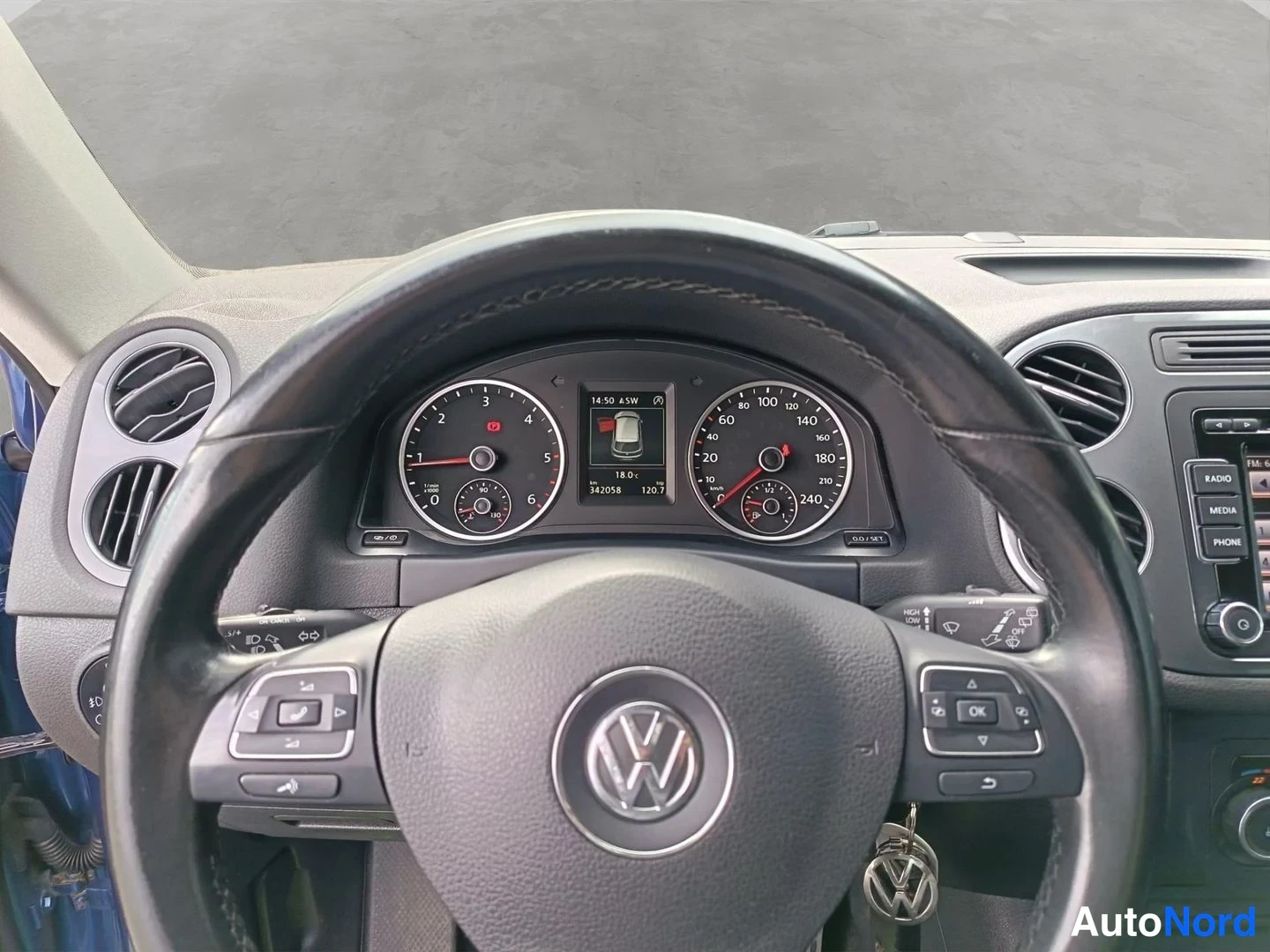Edestä: Ohjauspyörän ja kojetaulun näkymä: Volkswagen-merkki ohjauspyörässä, analogiset mittarit ja näyttö, jossa lukemat 342058 km ja 120,7.