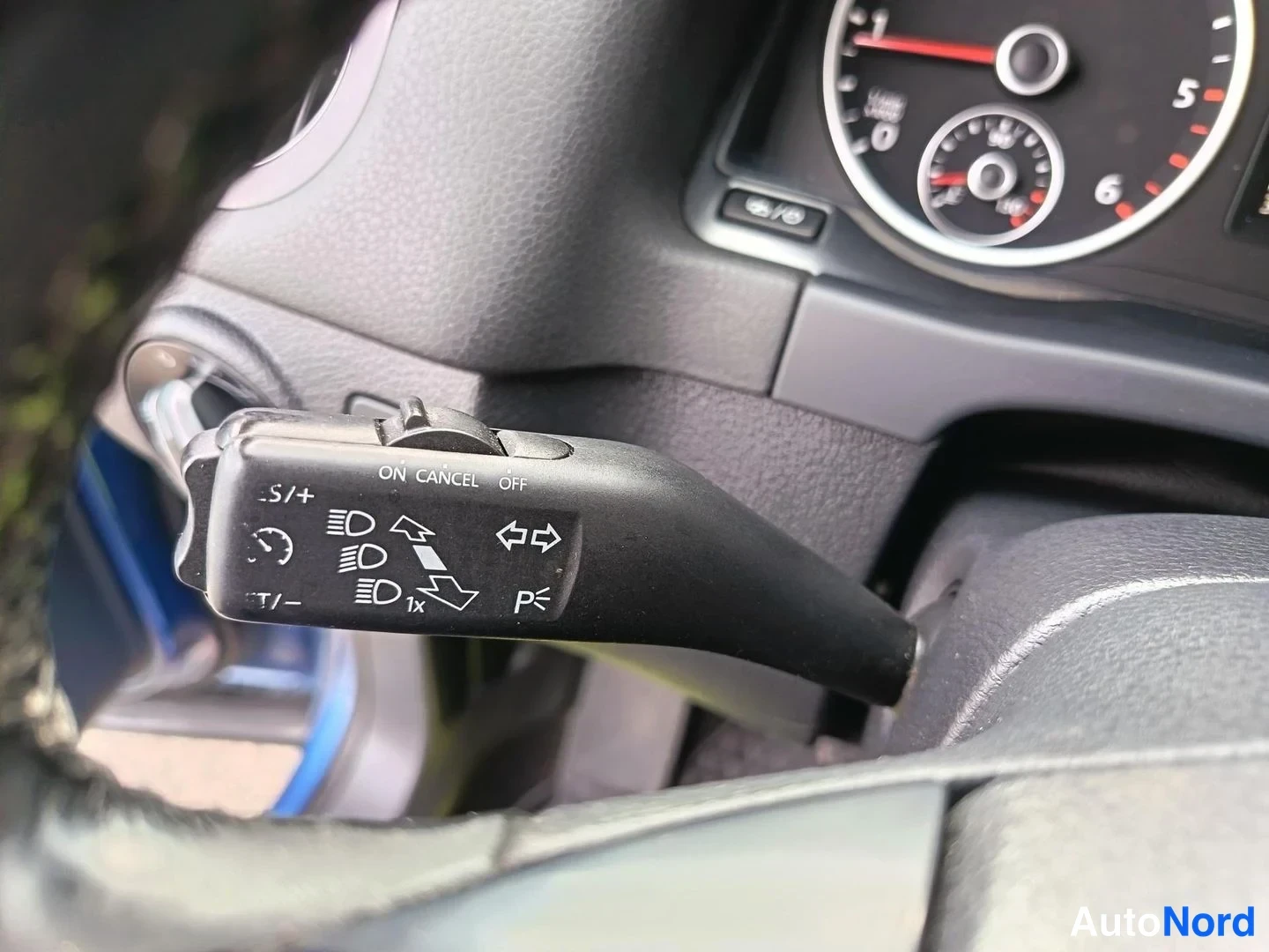 Yksityiskohta: Light control stalk behind the steering wheel showing headlight modes and indicators.