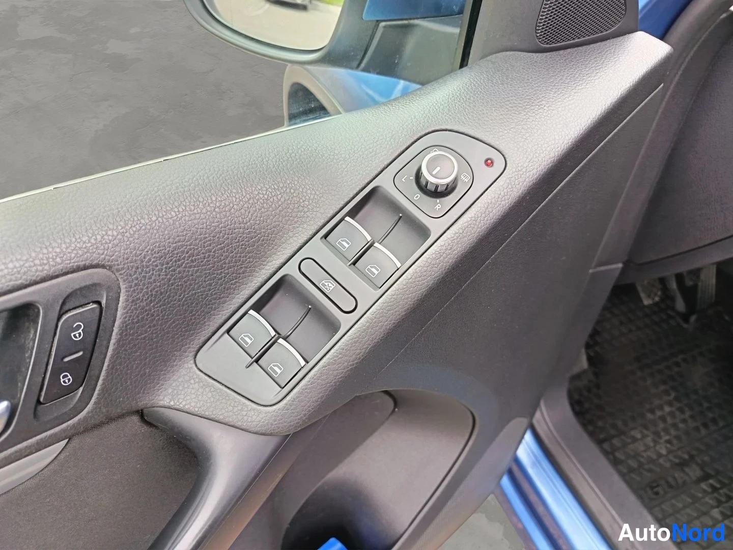 Ohjaamo: Driver side door panel featuring window switches, mirror adjustment dial, and central locking controls.
