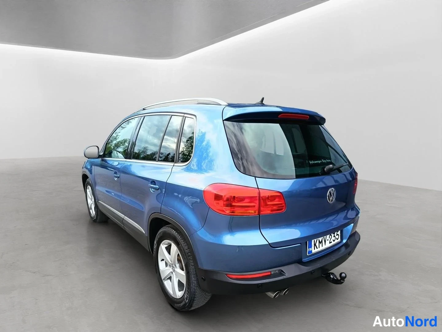 Takaviisto: Sinisen Volkswagen Tiguanin takakulma studiossa; rekisterikilpi ja vetokoukku näkyvissä.