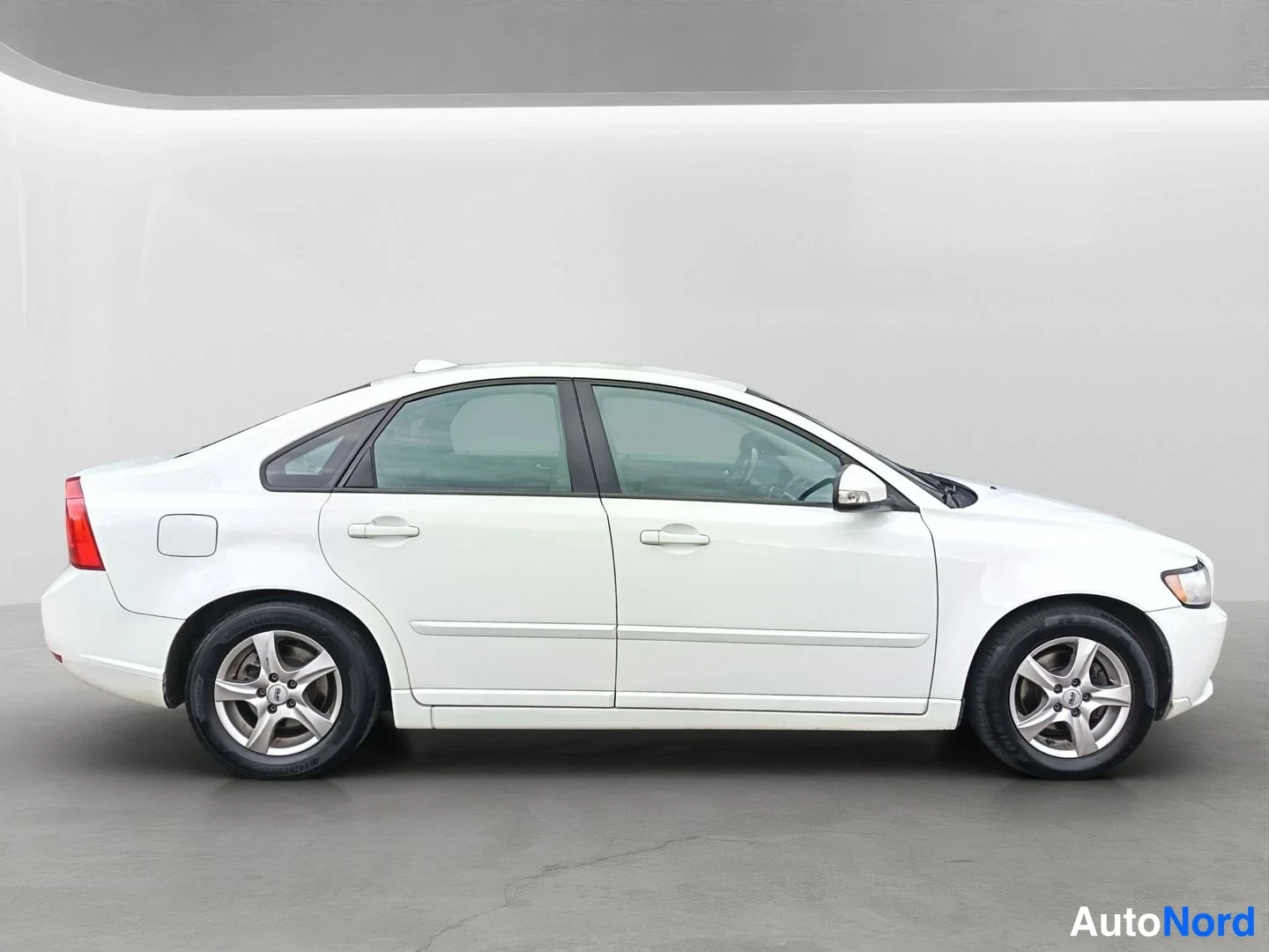 Sivulta: Side profile view of the white Volvo sedan showing four doors, wheel arches and roofline. Visible equipment: alloy wheels.