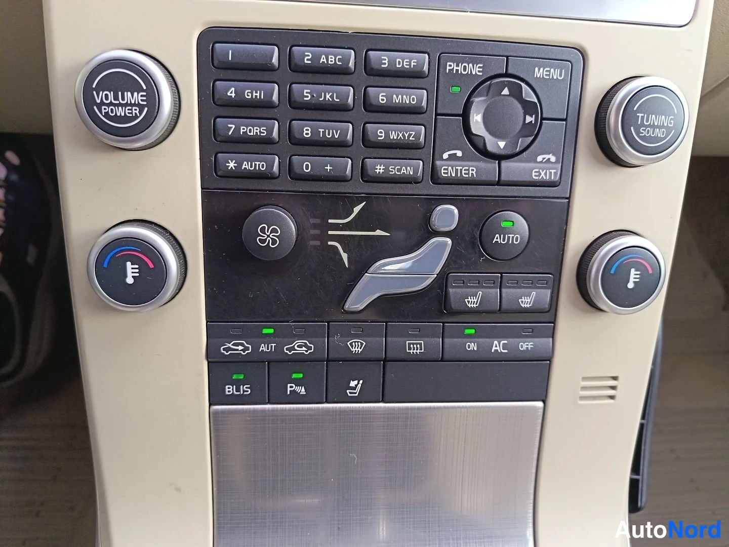 Yksityiskohta: Climate and vehicle-function control panel with dual temperature knobs, an AUTO climate button, heated-seat icons for two rows, air recirculation and defrost ke
