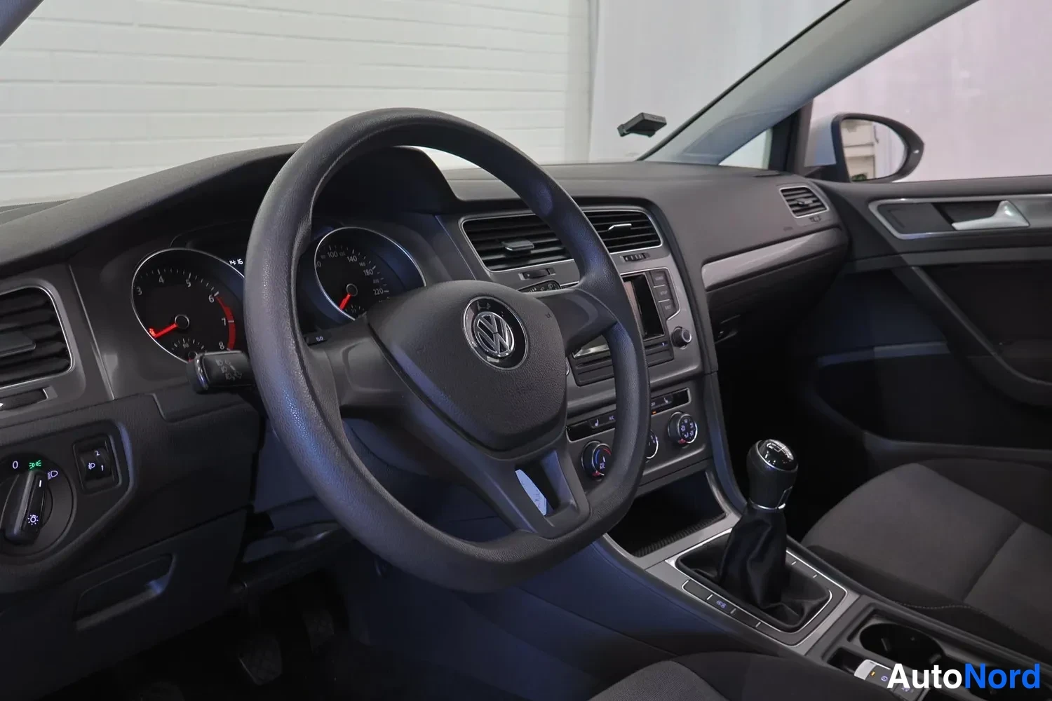 Ohjaamo: ohjauspyörä VW-logolla, mittarit, keskikonsoli, manuaalivaihdelaatikko ja ilmaversityöt.