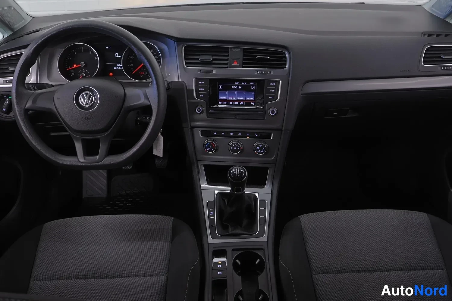 Ohjaamo: Sisäkuva, jossa on ohjaamo: kolmispuikkanen ohjauspyörä Volkswagen-logolla, mittaristo, keskikonsoli kosketusnäytollinen radio ja ilmastointi, manuaalivaihteist