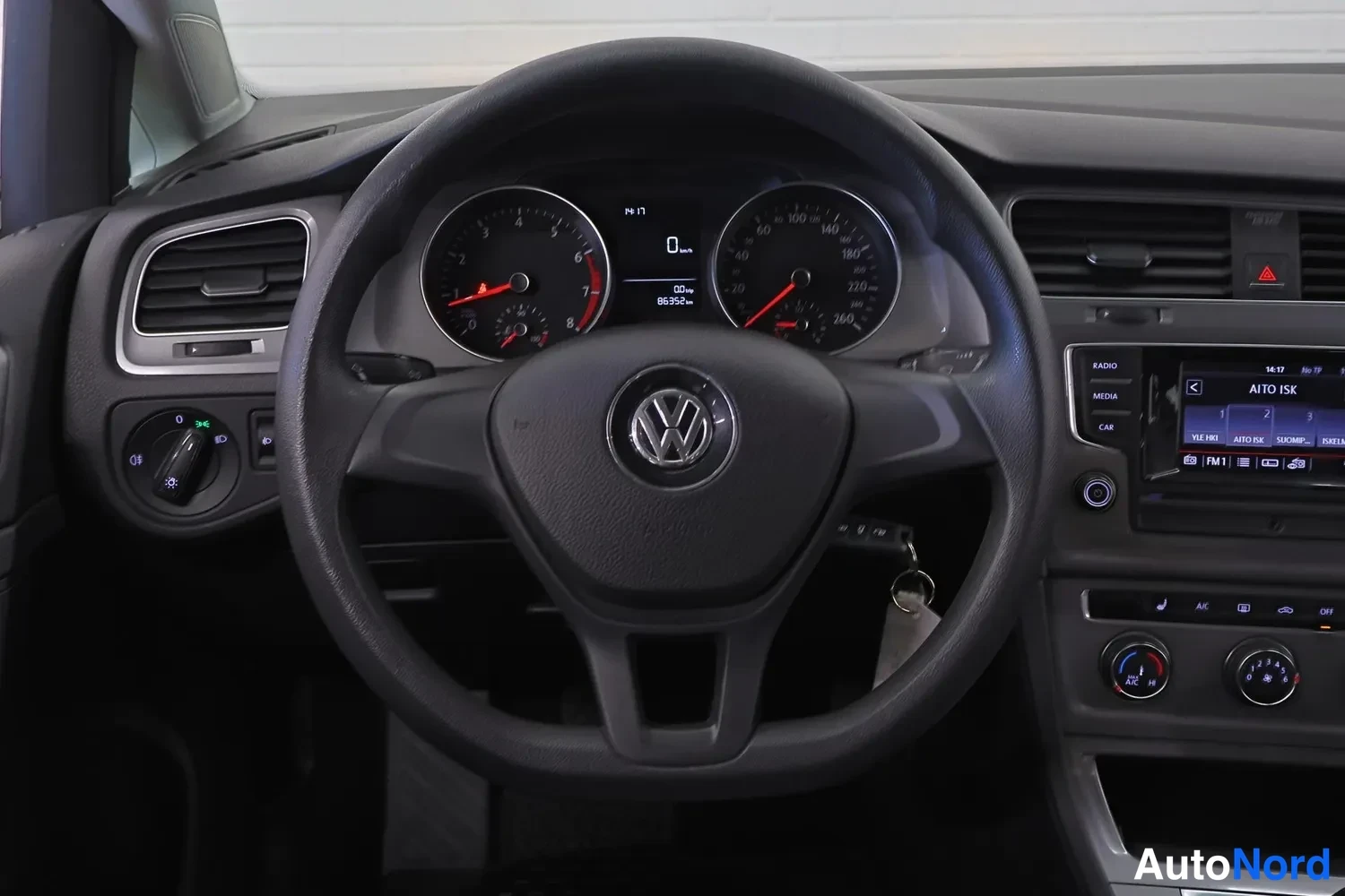 Etuistuimet: Ohjaamon lähikuva ohjauspyörän ympäriltä: Volkswagen-logo keskellä, digitaalinen mittaritaulu numerolla 86352 km, kosketusnäyttö oikealla, valot kytkin pyöreä v