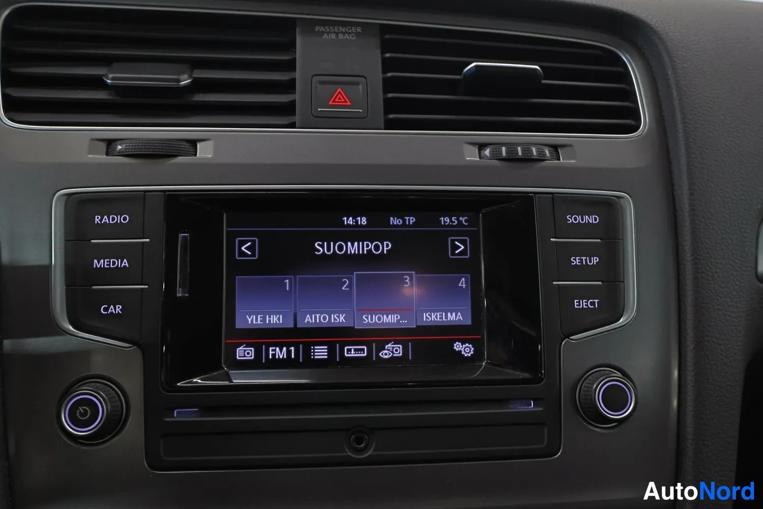 Ohjaamo: Center console close-up displaying an infotainment screen tuned to radio station SUOMIPOP and climate control set to 19.5 °C.