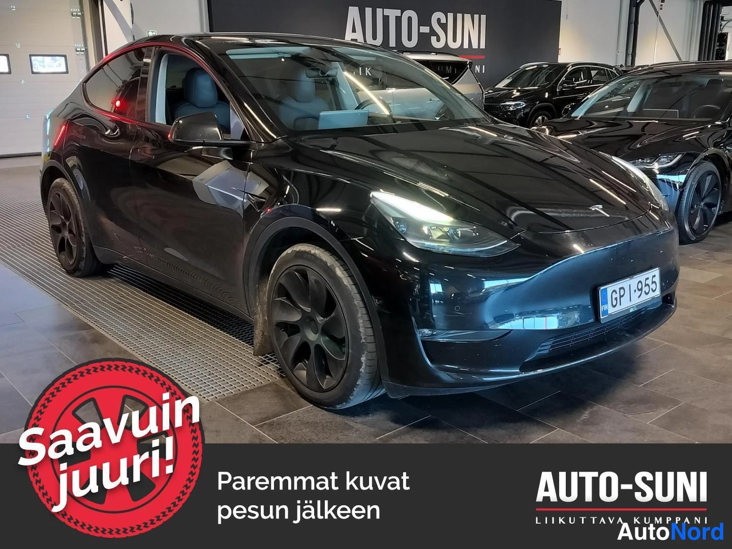 Etuviisto, nokka oikealle: Musta Tesla Model Y etukulmanäkymässä sisätiloissa, keula kuvan oikealla laidalla, rekisterikilpi GP-955.