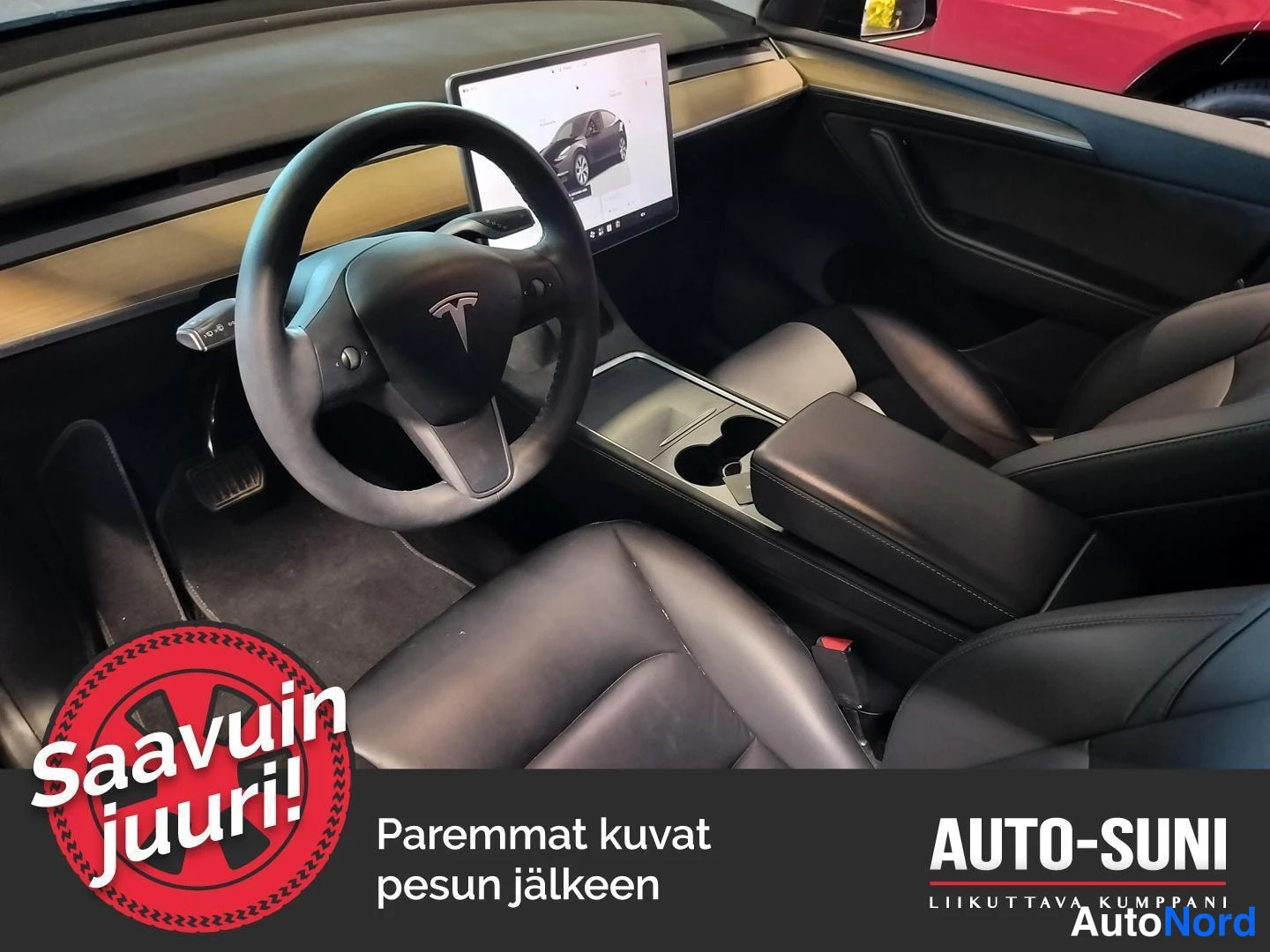 Edestä: Auton sisätila: ohjauspyörä ja keskinäytön vasen etuistuin näkyvät, tummat penkit.