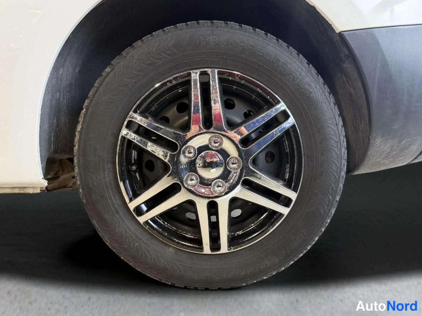 Yksityiskohta: Irrotettu renas ja kiiltävä pölykansi, Hankook-rengas näkyvissä.