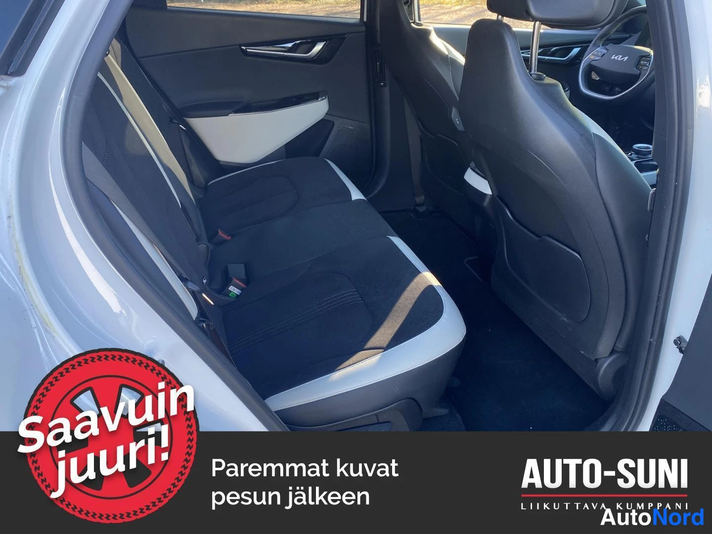 Yksityiskohta: Takapenkki ja etuistuimet näkyvät avaamasta ovesta kuvattuna; tummat kangasistuimet ja kuljettajan puolen ohjauspyörä.