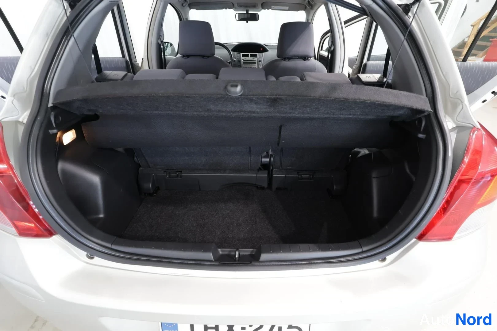 Takaa: Avoimessa tavaratilassa näkyvät taitettavat takapenkit ja kuormatila; auto valkoinen.