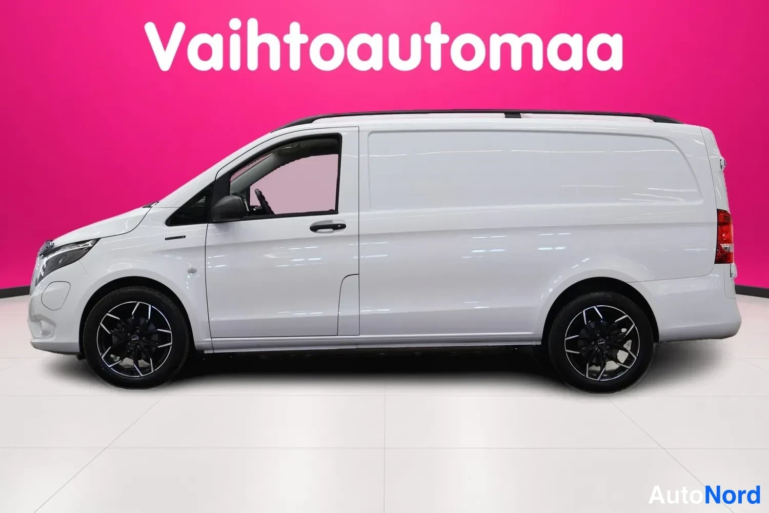 Etuviisto, nokka vasemmalle: Valkoinen pakettiauto kuvattuna kolmasosaedusta, keula vasemmalla; mustat kevytmetallivanteet ja mustat kattokiskot.