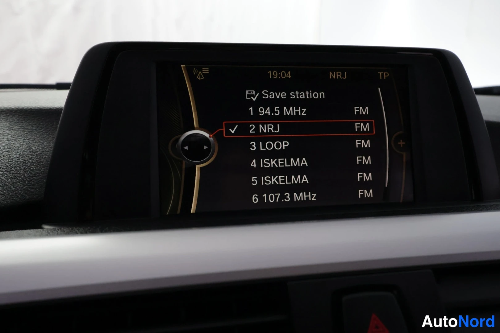 Muu: Auton infotainment-näyttö radion asemalistassa: valittuna NRJ (2), muina vaihtoehtoina 94.5 MHz, LOOP, ISKELMA ja 107.3 MHz, kaikki FM; yläpalkissa kello 19:04,