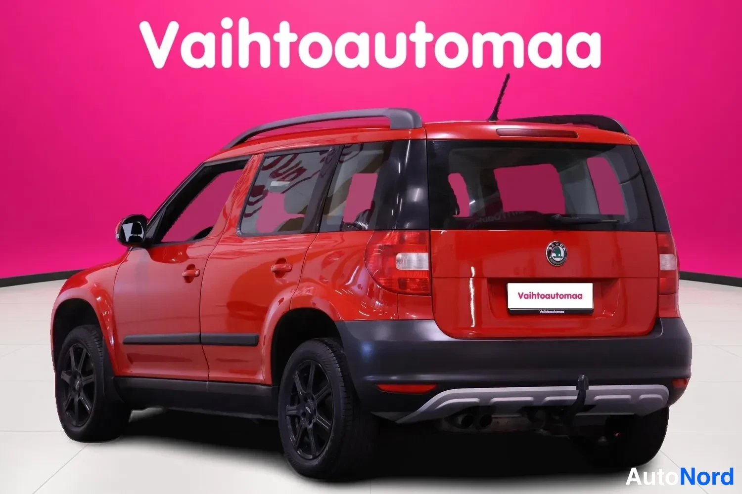 Takaviisto: Punainen Skoda Yeti takakulmakuvasta toisesta suunnasta, takaosa ja kylki kuvassa; vetokoukku, kattokaiteet ja mustat vanteet.