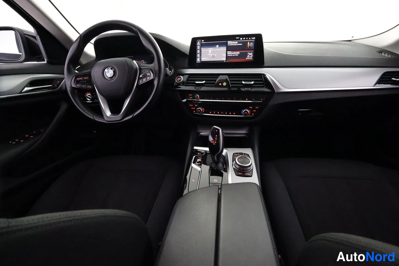 Etuistuimet: Ohjaamo kuljettajan puolelta: BMW-ohjauspyörä, keskinäyttö karttanäkymällä, automaattivaihteen valitsin ja iDrive-ohjain keskikonsolissa.