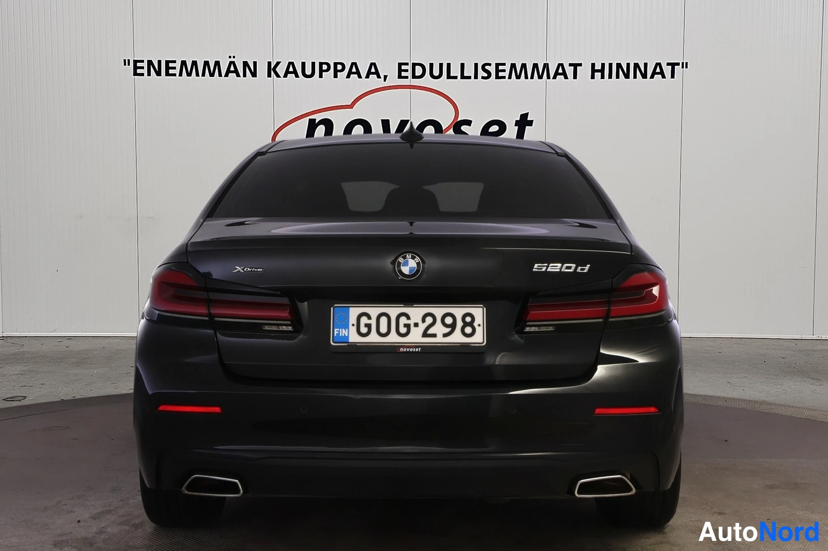 Takaa: Mustan BMW-sedanin perä suoraan takaa; kannessa 520d- ja xDrive-merkinnät, kaksoispakoputket ja rekisterikilpi.