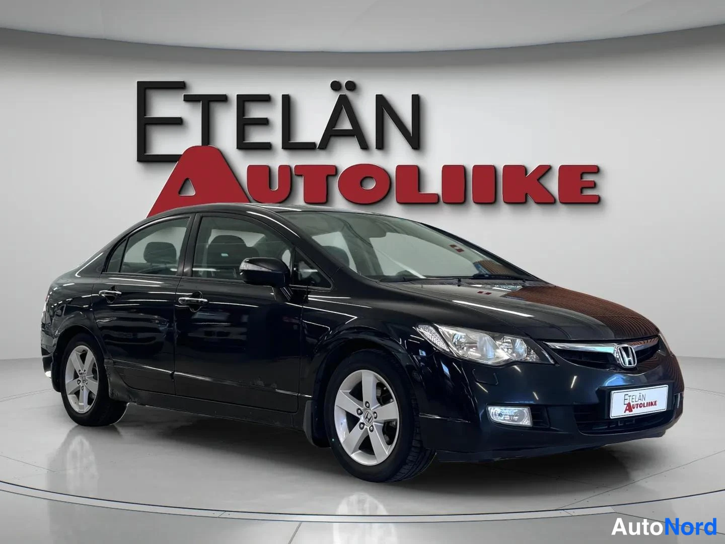 Etuviisto, nokka oikealle: Musta Honda Civic -sedan etuviistosta oikealta, kokovärikkäät pennit ja hopeiset vanteet.
