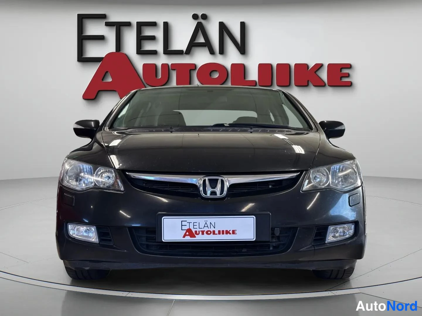 Edestä: Musta Honda Civic -sedan suoraan edestä, kromattu etusäleikö ja sumuvalot.