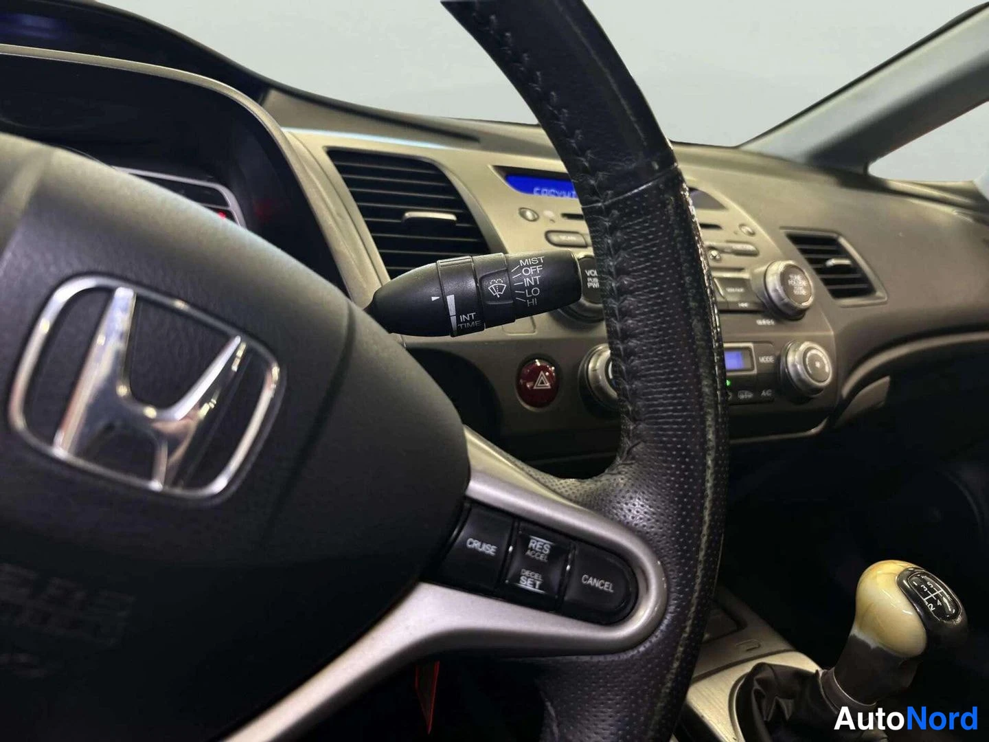 Edestä: Honda-ohjauspyörä cruise control -napeilla (CRUISE, RES, CANCEL, SET), vikselin vilkkuvalot (MIST, OFF, INT, LO, HI), keskiteline ja manuaalivaihteen keppi.