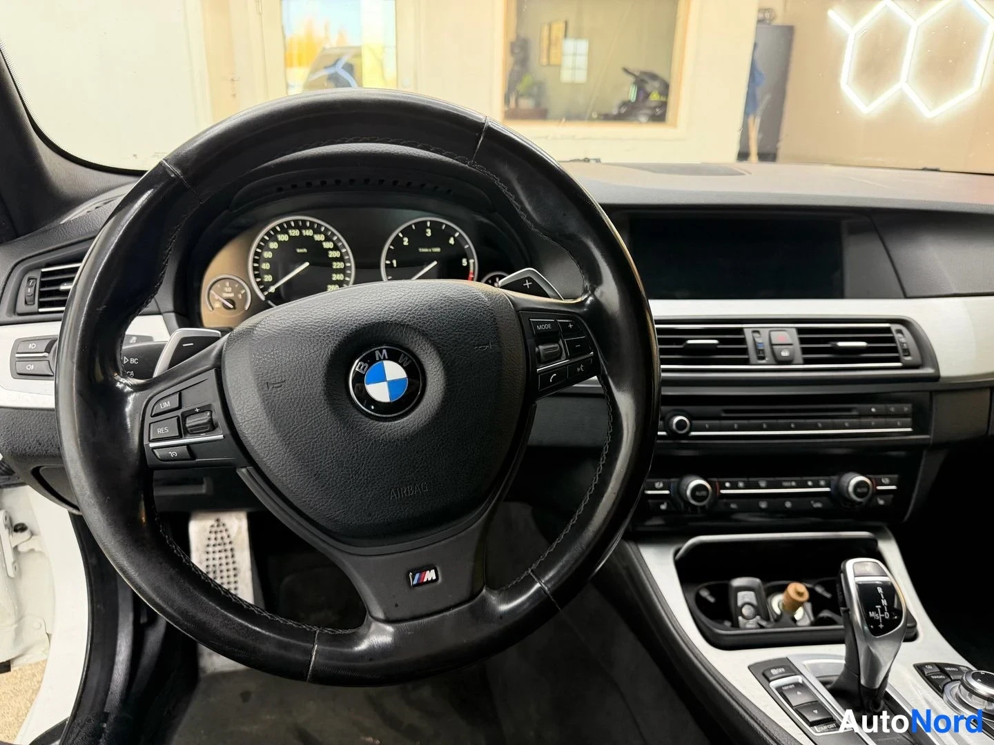 Muu: Musta BMW-ohjauspyörä, jonka puhalluksessa on M-merkki ja takana lapamaiset vaihdonvaihtajat; mittaristo, automaattivaihteen valitsin ja keskikonsolin säätimet.