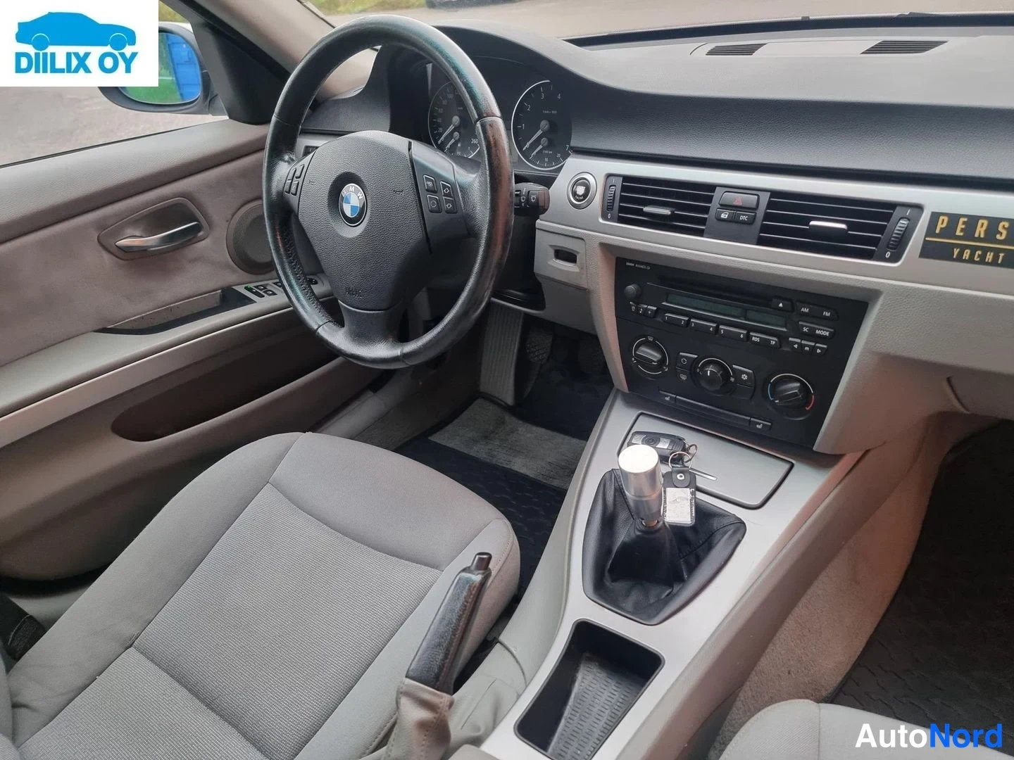 Yksityiskohta: Auton sisätilat: BMW-ohjauspyörä, kojelauta, radio-CD-soitin ja manuaalivaihteiston vaihdekeksi keskikonsolissa.