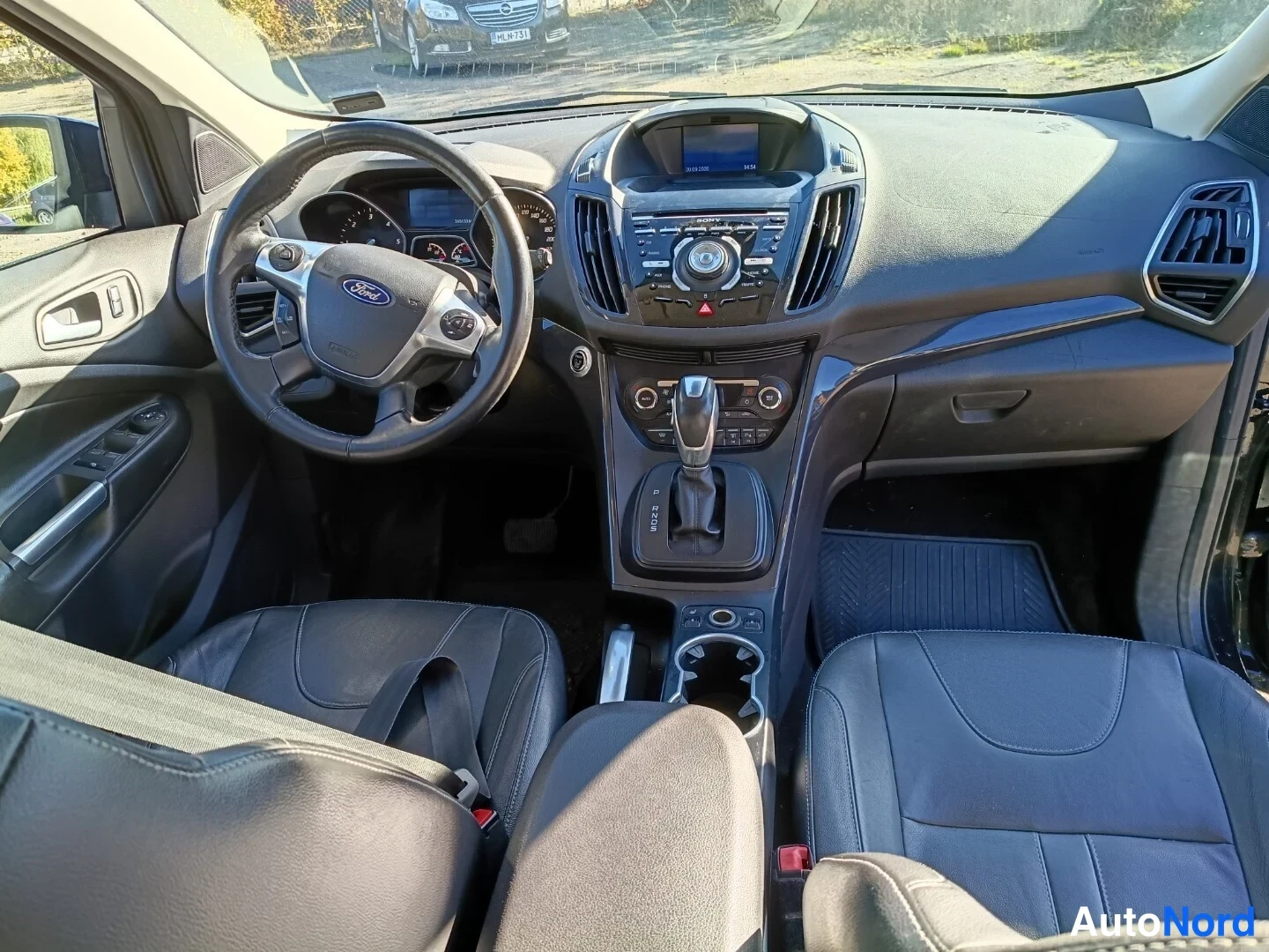 Muu: auton sisätilan etunäkymä: Ford-ohjauspyörä, kojelauta, Sony-radiopaneeli ja automaattivaihteen valitsin, mustat penkit