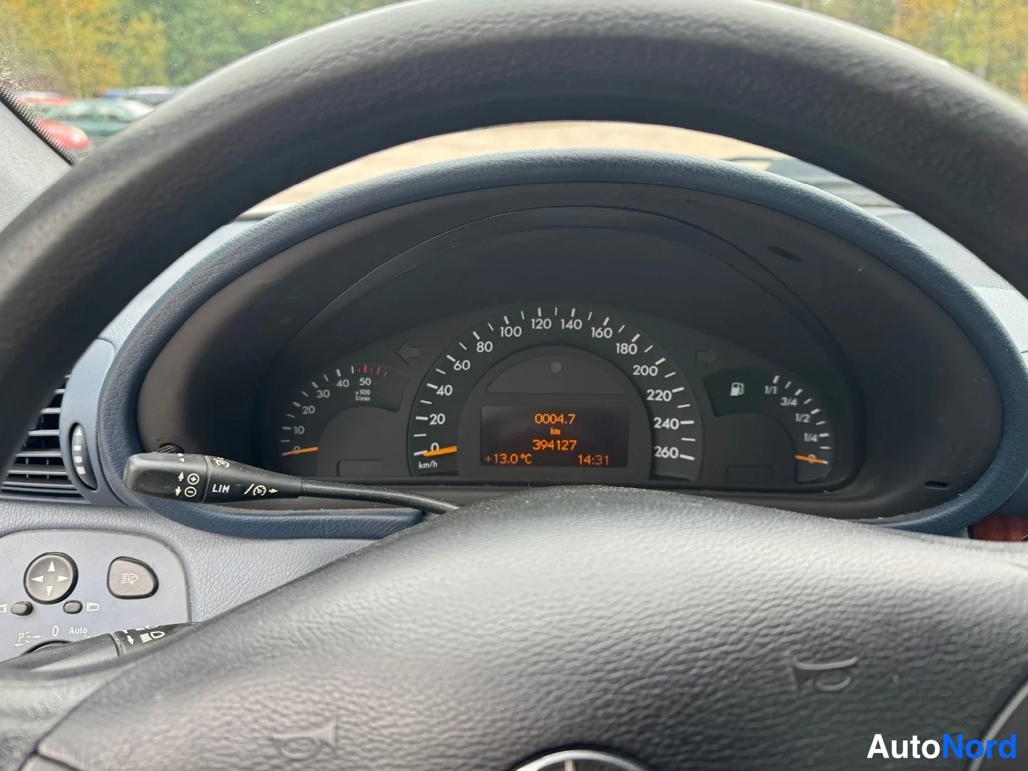 Yksityiskohta: Mittaristosta näkyvät nopeusmittari ja merkkivalot, kilometrilukema 394 127 km.