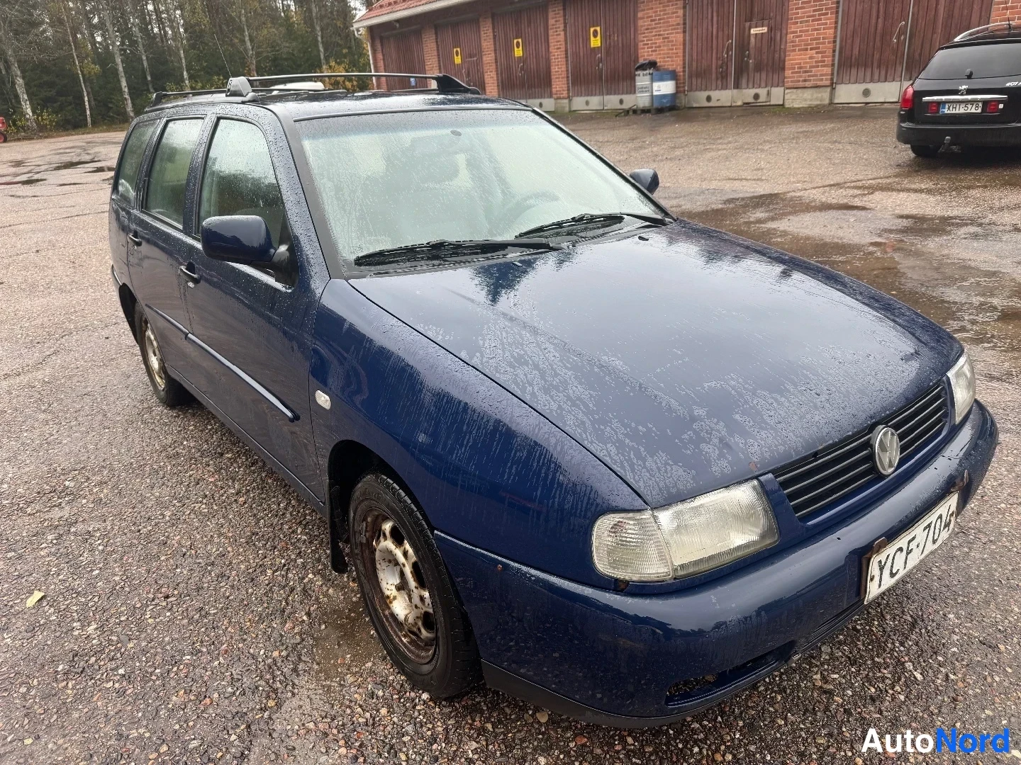 Etuviisto, nokka oikealle: Tummansininen Volkswagen Polo -farmari kuvattuna etukulmasta, keula oikealla; kyljen ovet, kattokaiteet ja rekisterikilpi näkyvät.