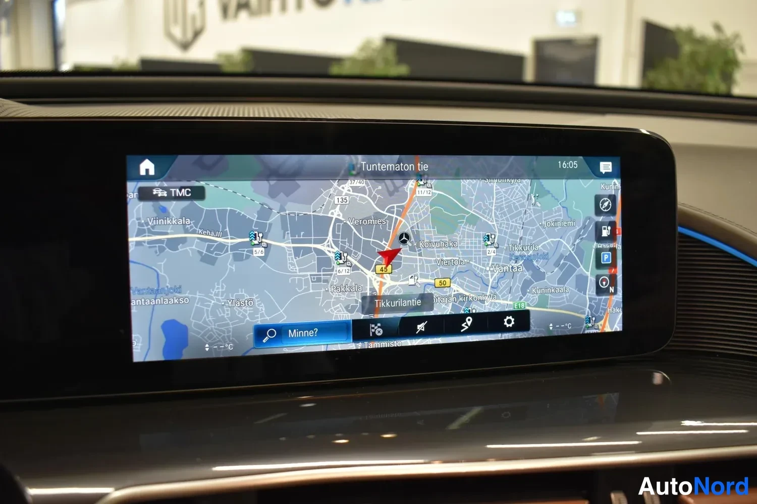 Edestä: Infotainment-näytön navigointikartta Suomessa, otsikko 'Tuntematon tie' ja hakukenttä 'Minne?', kello 16:05.