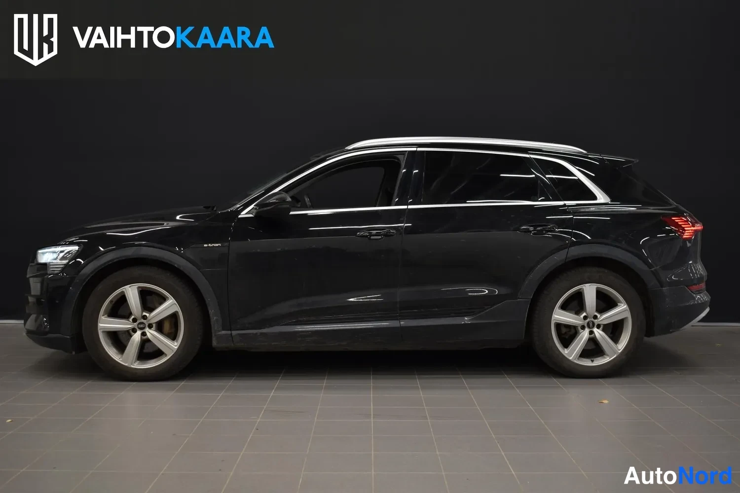 Etuviisto, nokka vasemmalle: Audi e-tron sivuprofiilista vasemmalta; tumma runko, kattokaiteet ja viisikehäiset pyörät.