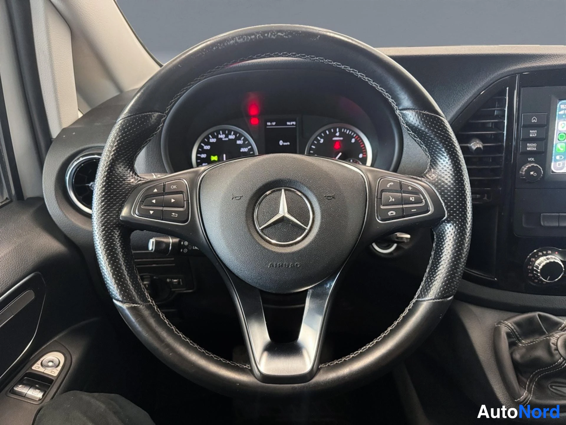 Edestä: Mercedes-tähtimerkitty ohjauspyörä, mittaristo ja keskikäyttöpaneeli, jossa näkyy CarPlay-ruutu ja automaattivalitsin.
