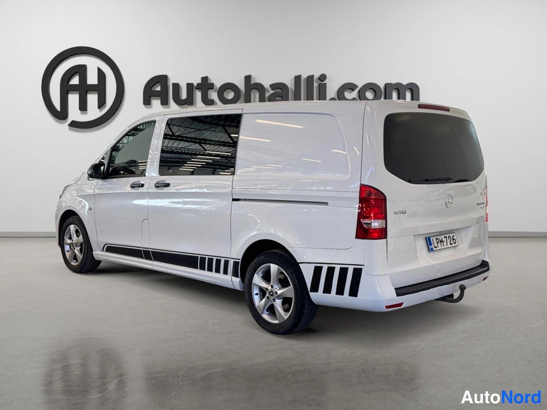 Takaviisto: Valkoinen Mercedes-Benz Vito -pakettiauto kuvattuna takaviistosta; takavalot, takaluukku ja vasen kylki näkyvät, sivussa ja takapuskurissa mustia raidakoristeit