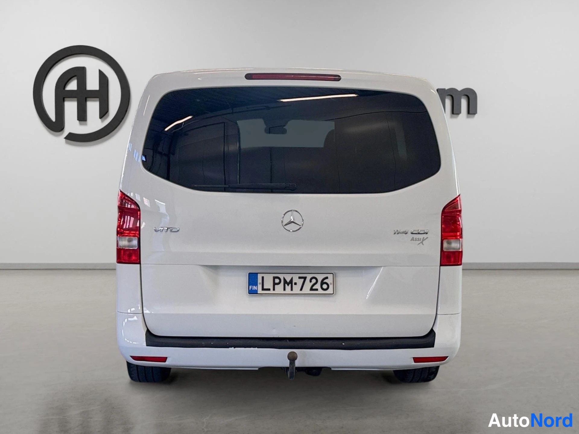 Takaa: Valkoisen Mercedes-Benz Vito -pakettiauton takaosan suora etunäkymä; rekisterikilpi, savetut takalasinpuhdistin ja vedon kysyntäosasoveljet.