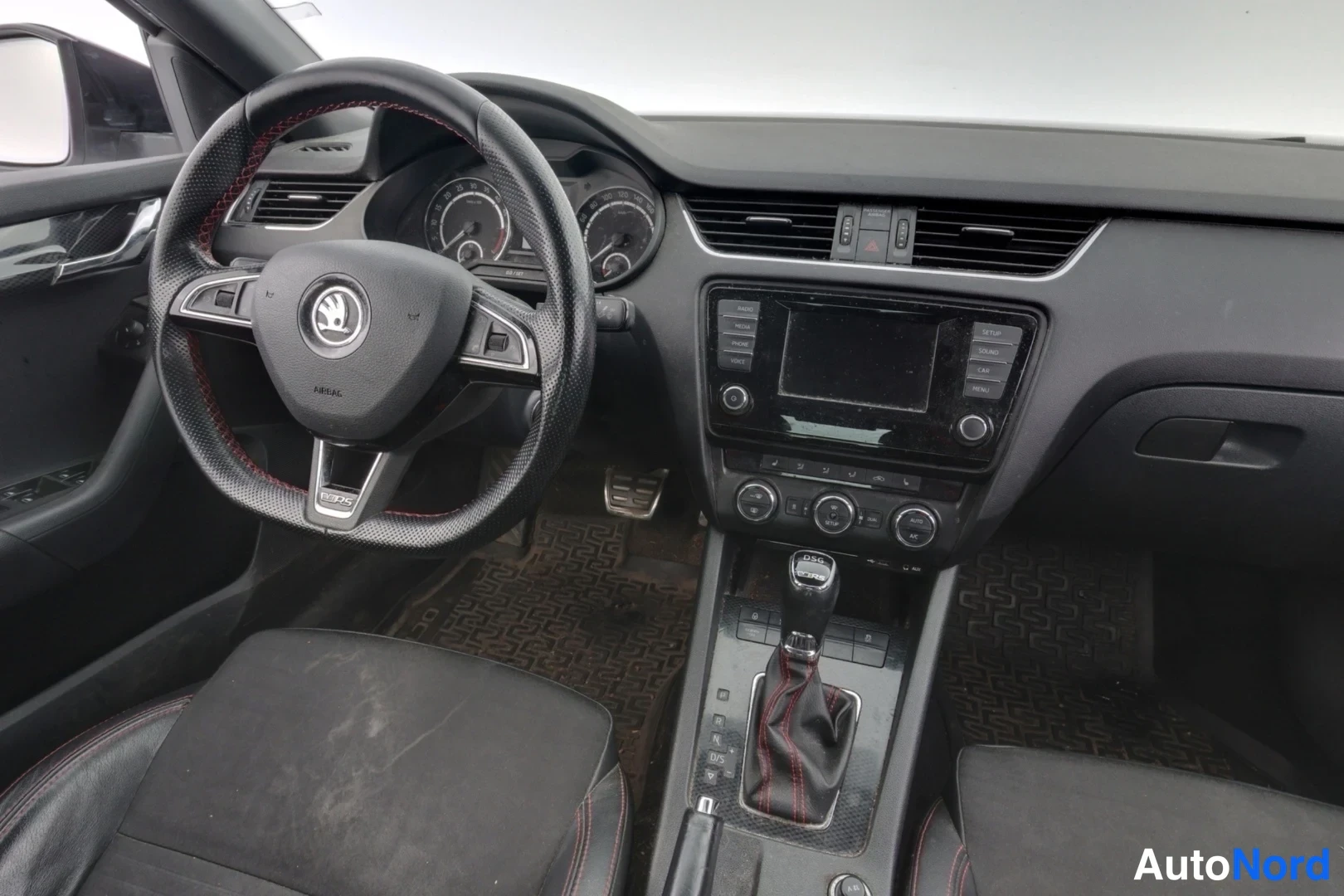Muu: Ohjaamo vasemmalta: Skoda-merkkiohjauspyörä punaisilla ompeleilla, analogiset mittarit, keskikonsolissa kosketusnäyttö ja automaattivaihteen valitsin.