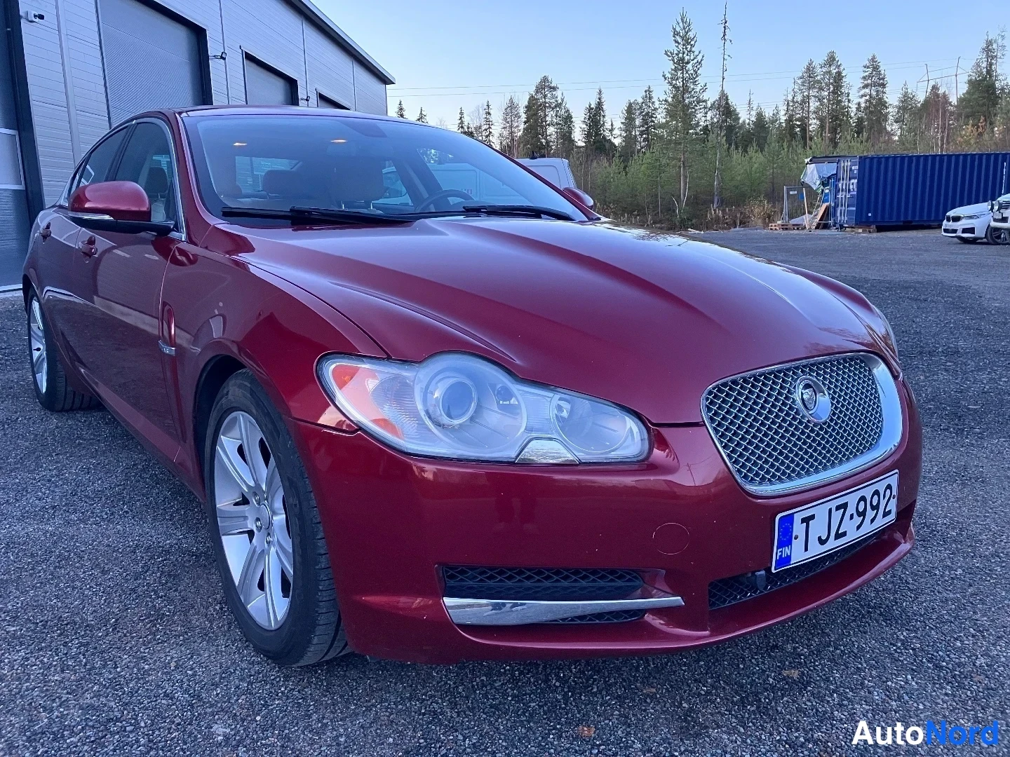 Etuviisto, nokka oikealle: Punainen Jaguar XF, etuosa ja vasen sivu näkyvissä grilleri ja rekisterinumero
