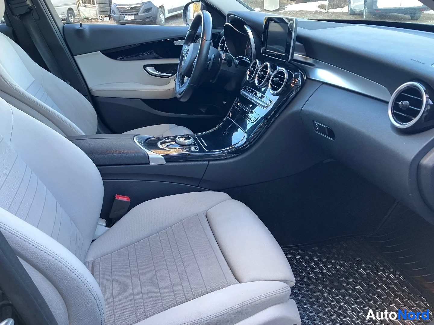 Ohjaamo: Interior view showing front driver and passenger seats with beige fabric upholstery, black dashboard, central infotainment screen, air vents, steering wheel and