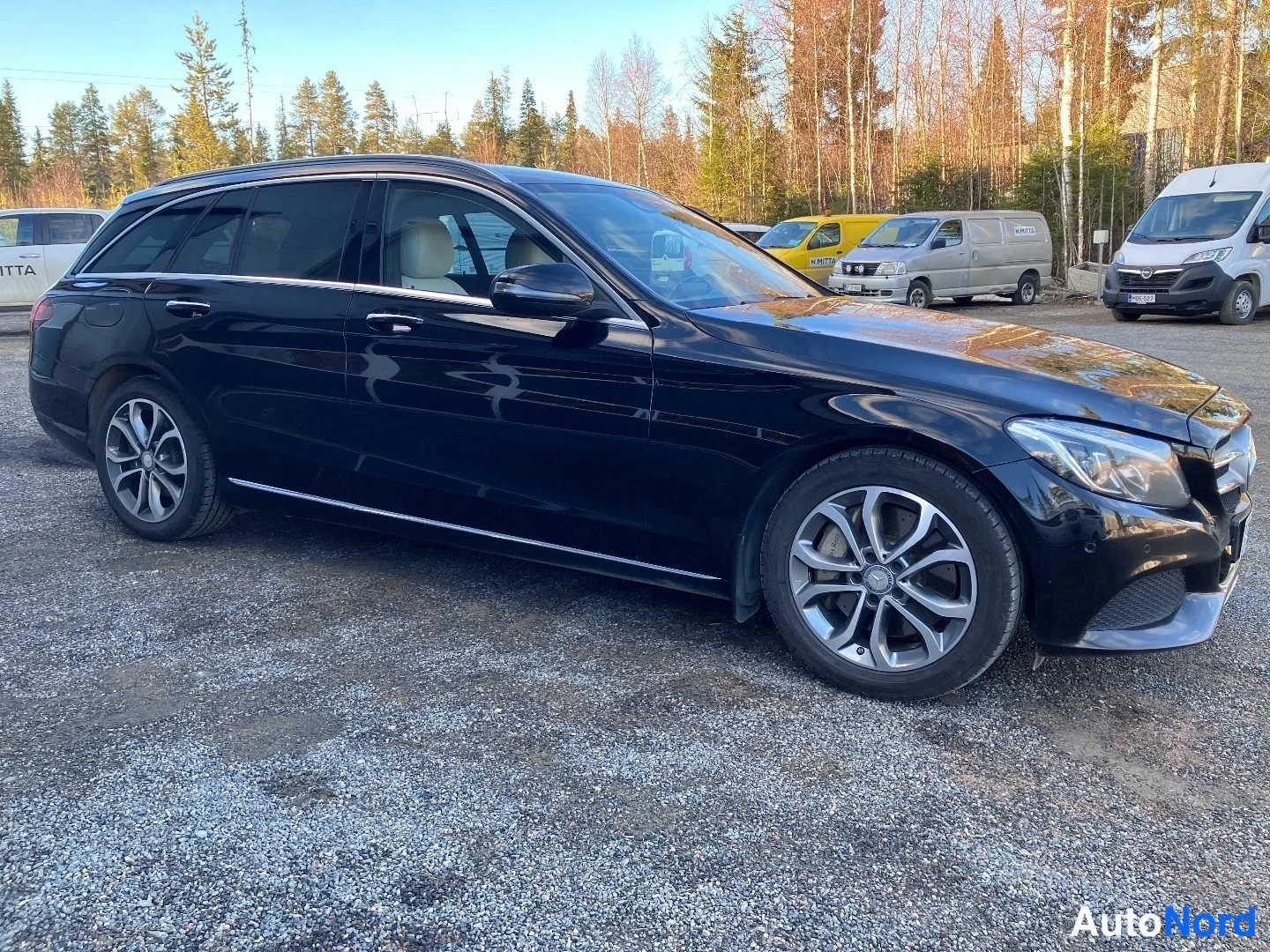 Sivulta: Vasen sivu ja etupää. Näkymä osoittaa, että auto on tumma farmarikorinen (C-sarja) oikealla ajosuunnassa olevilla alumiinirenkailla.